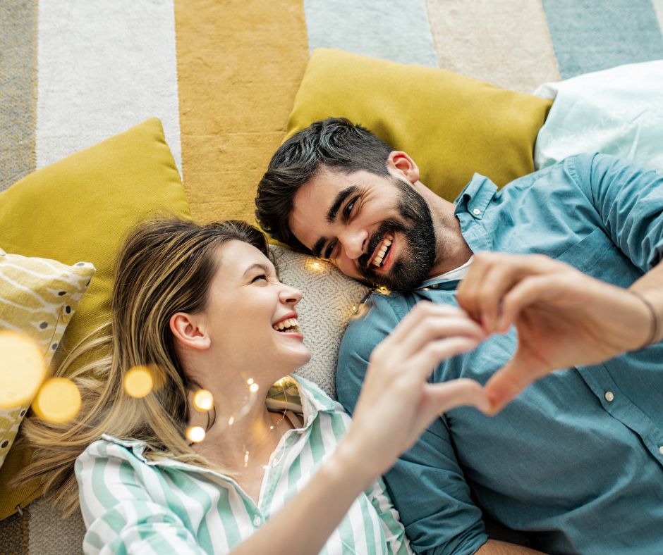 couple laying down making heart with hand