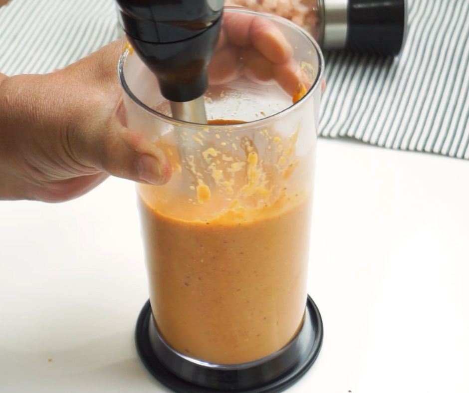 using an immersion blender on the butter chicken sauce