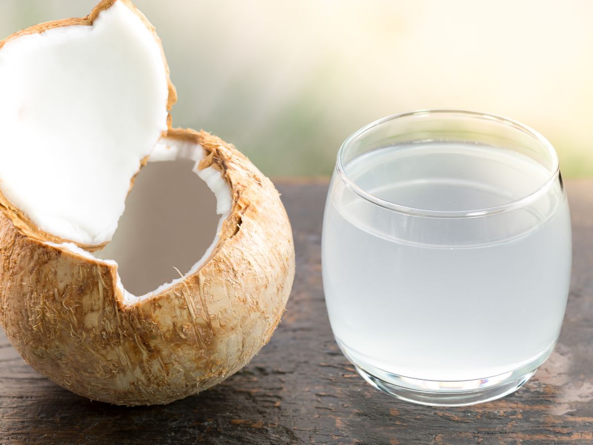 coconut water and coconut rum in a glass sitting next to a coconut