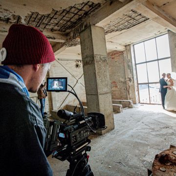 person with a video camera and wedding couple