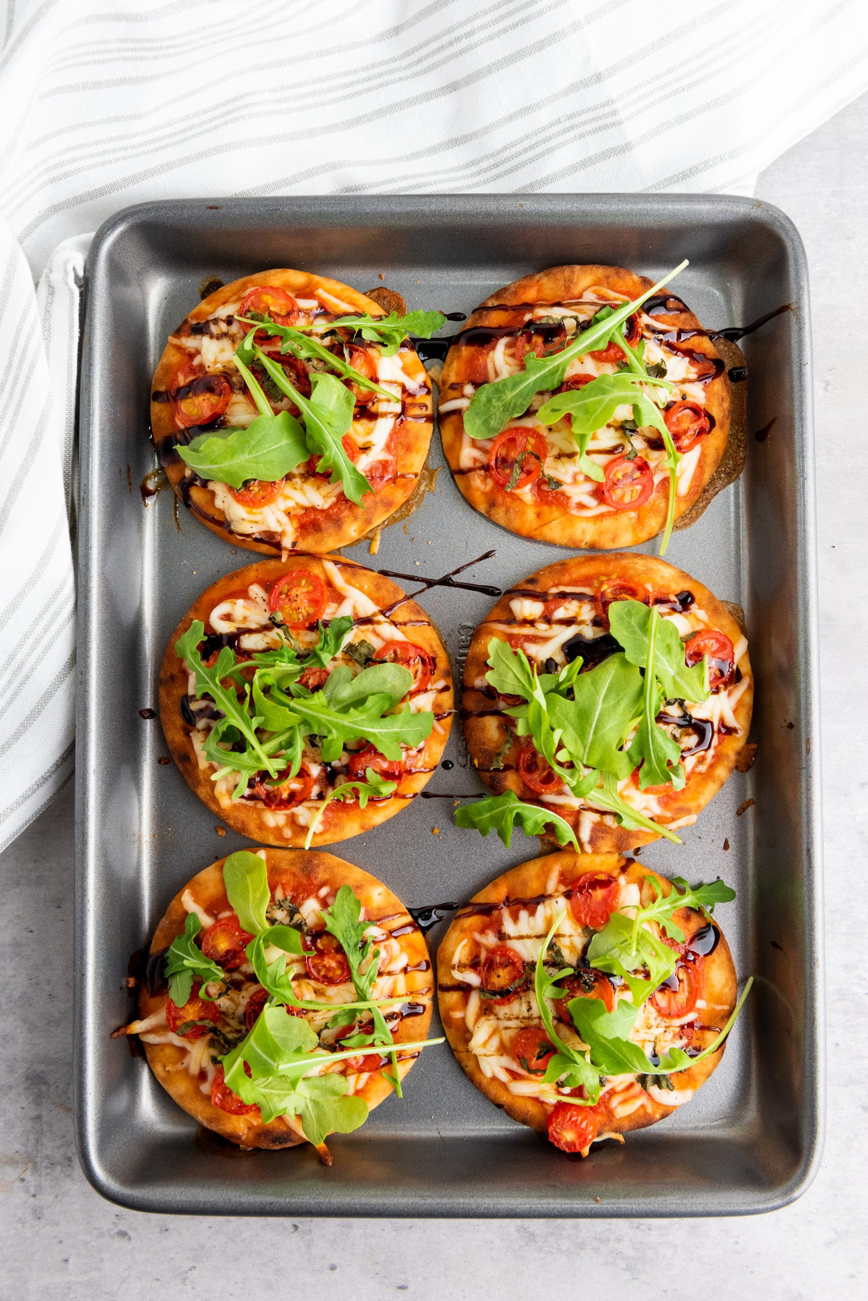 baked caprese pizzas on a baking sheet