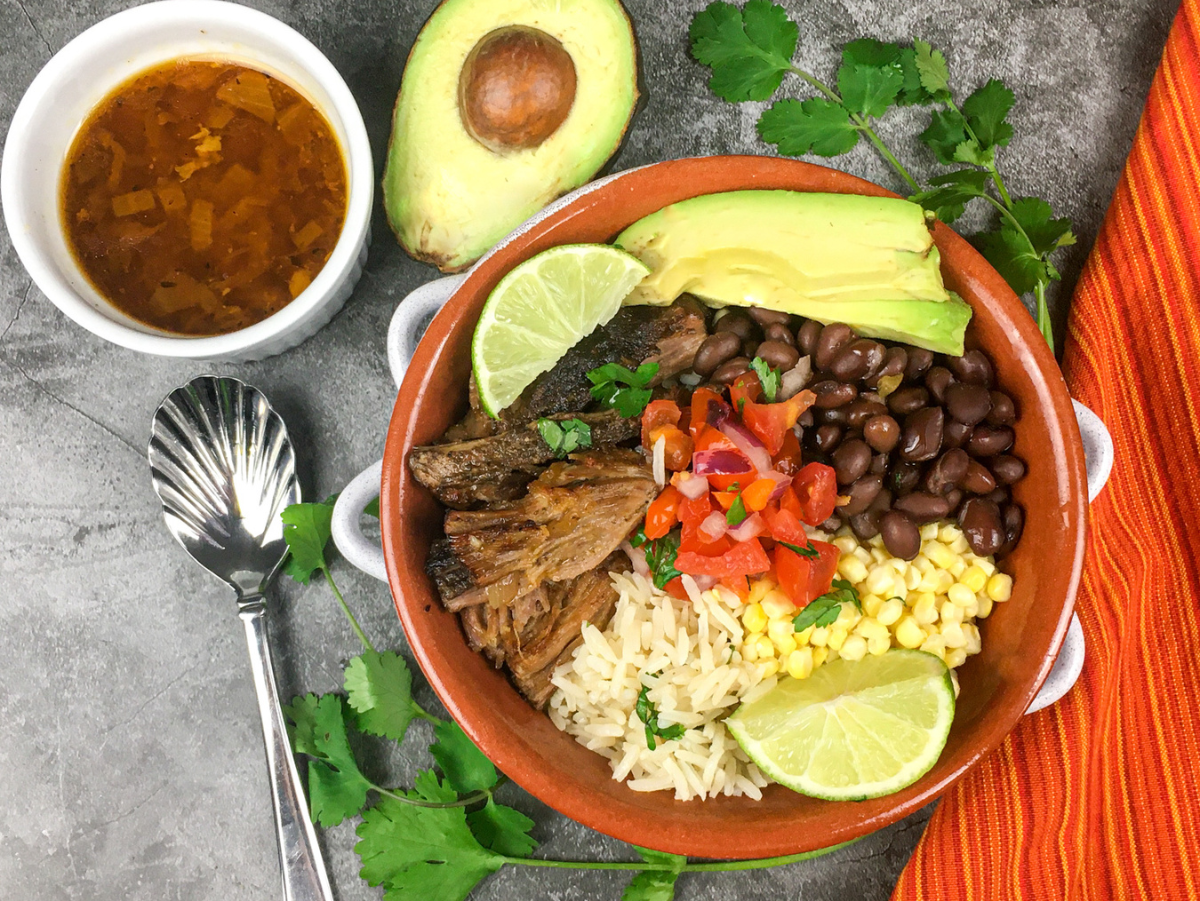 chipotle copycat carnitas in a reddish bowl with avocado and onions