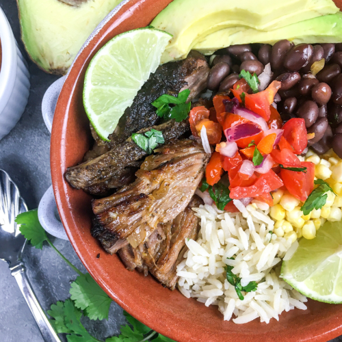 chipotle copycat carnitas in a reddish bowl with avocado and onions