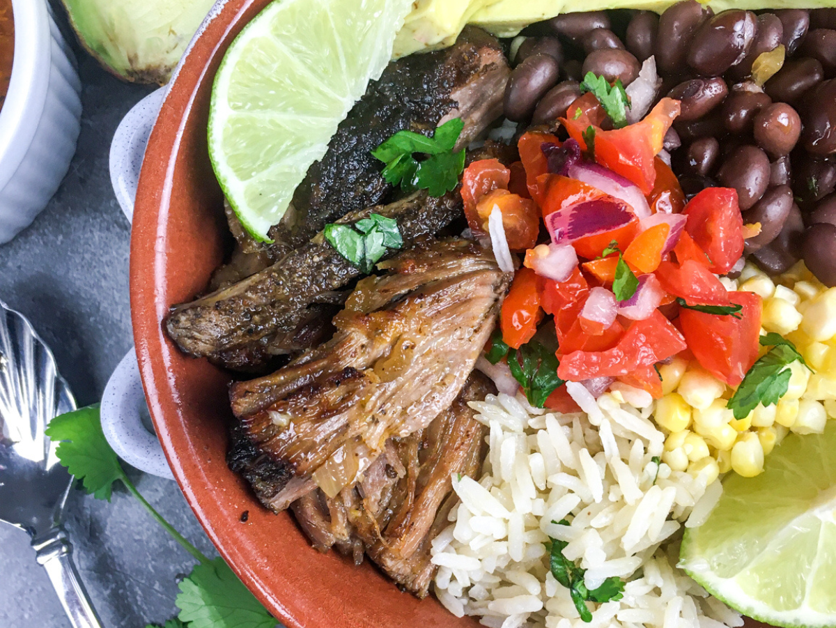 chipotle copycat carnitas in a reddish bowl with avocado and onions