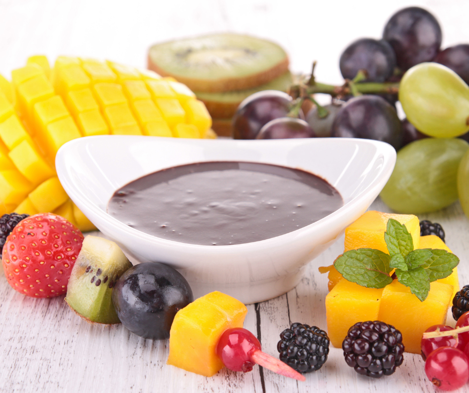 chocolate syrup in a bowl with fruit skewers