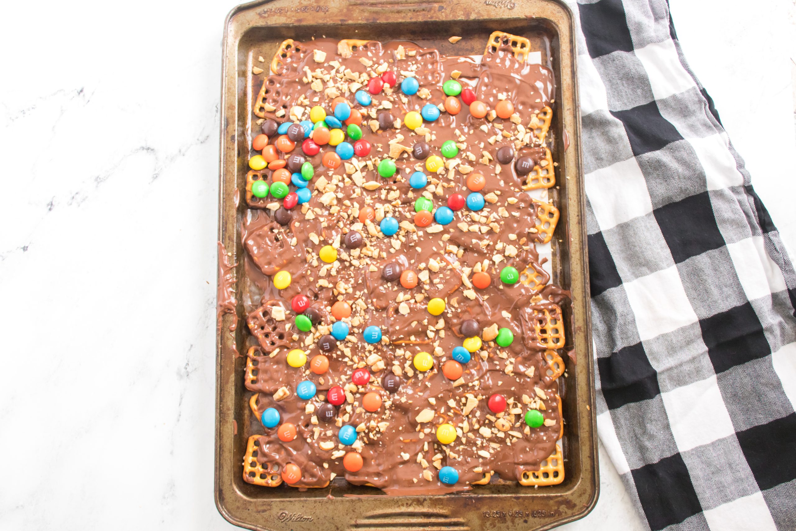 Melted chocolate spread across the pretzels with m&ms and crushed peanuts 