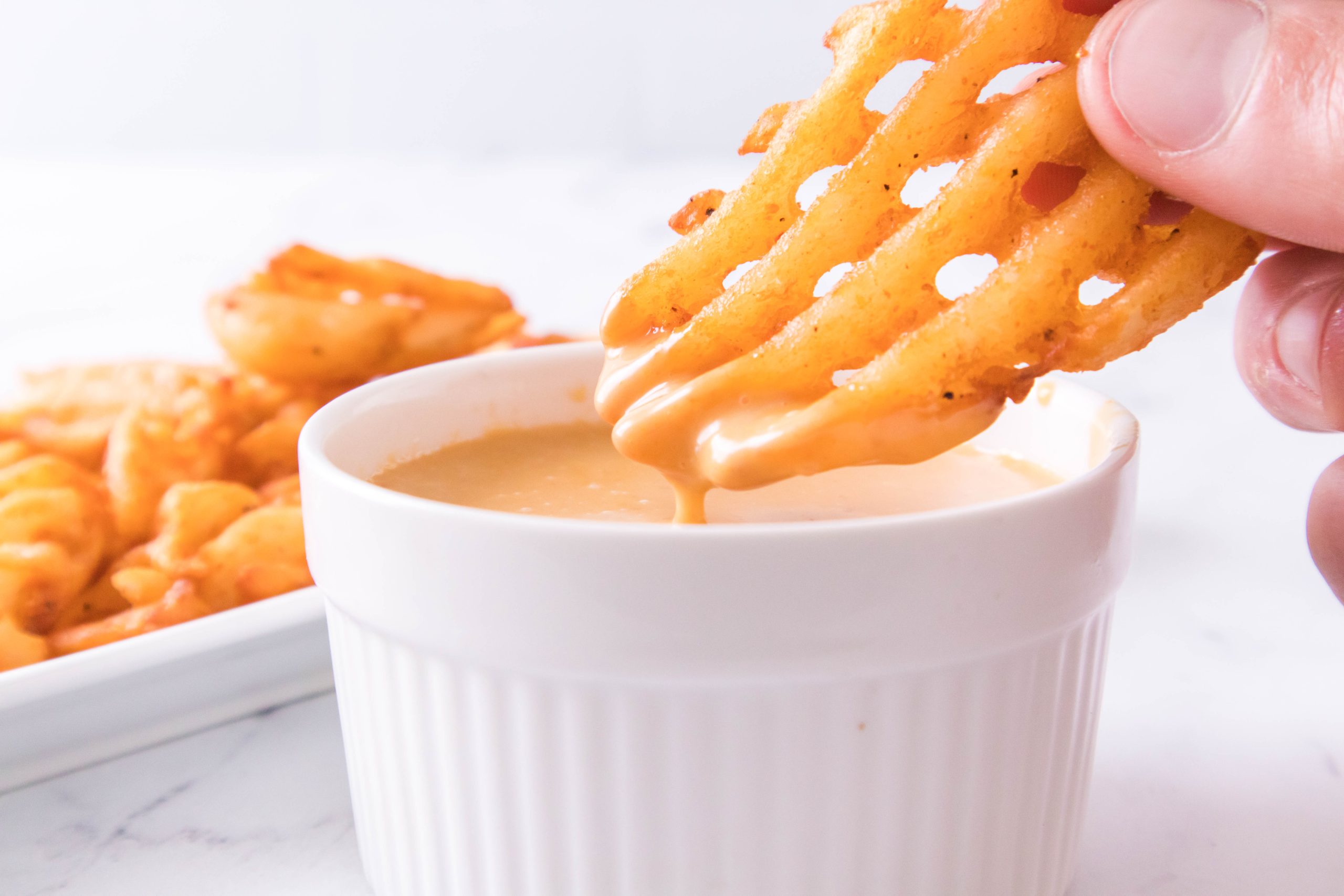 dipping waffle fries in Copycat Chick Fil a Sauce