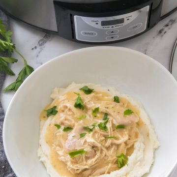 chicken and gravy in a crock pot recipe in a white bowl