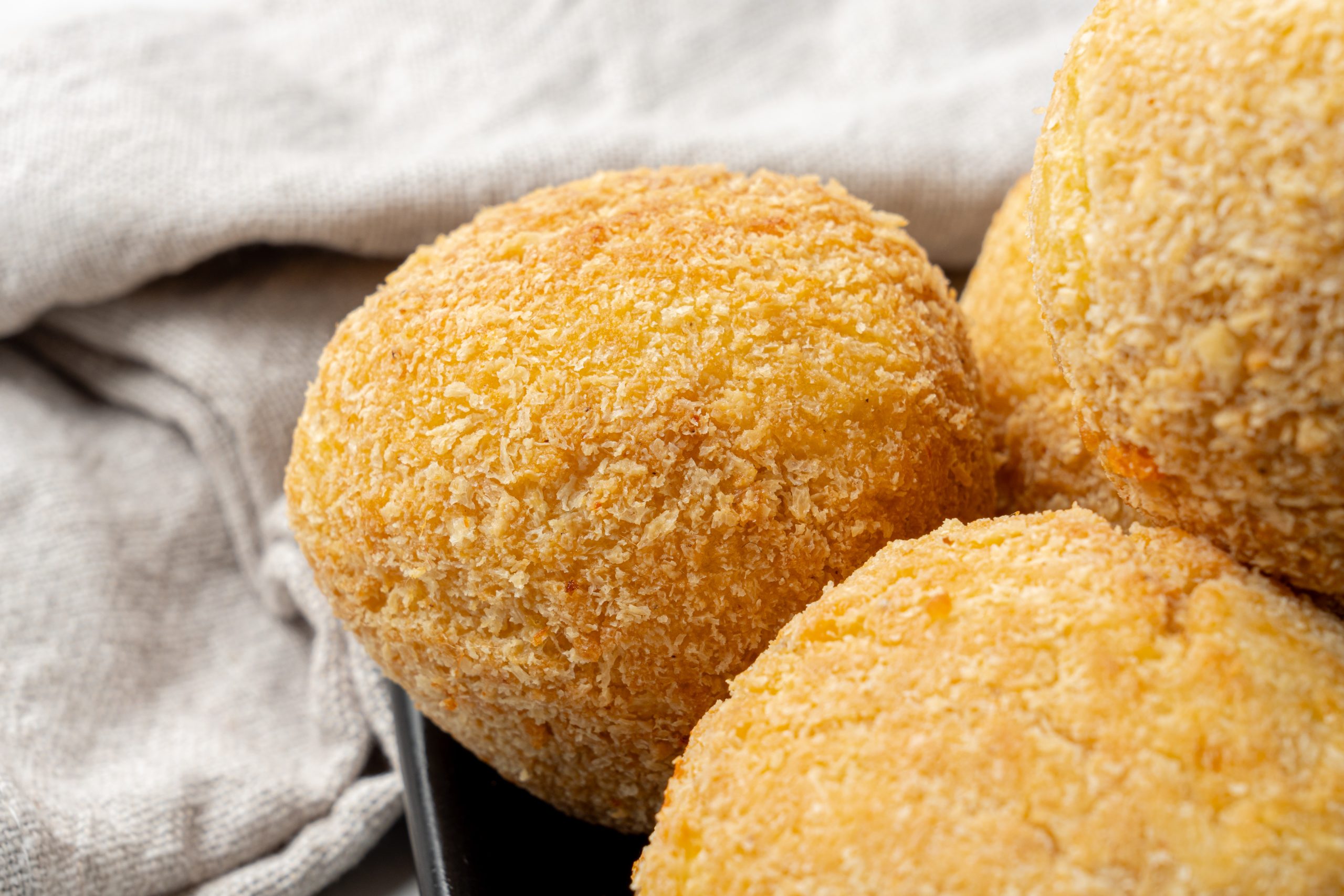 Golden brown potato cheese croquettes coated in breadcrumbs, served on a black plate 