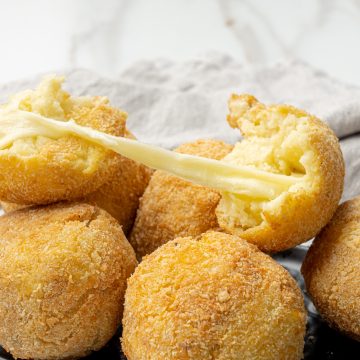 Golden brown potato cheese croquettes coated in breadcrumbs, served on a black plate