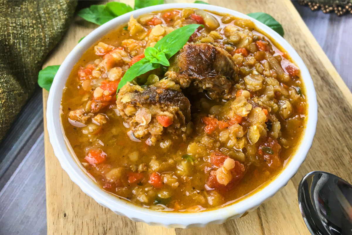 spanish lentil soup with chorizo served in white bowl on wooden board