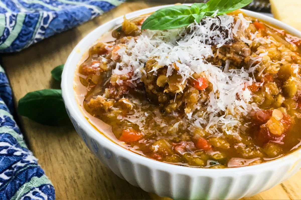 chorizo lentil soup topped with parmesan cheese and fresh basil