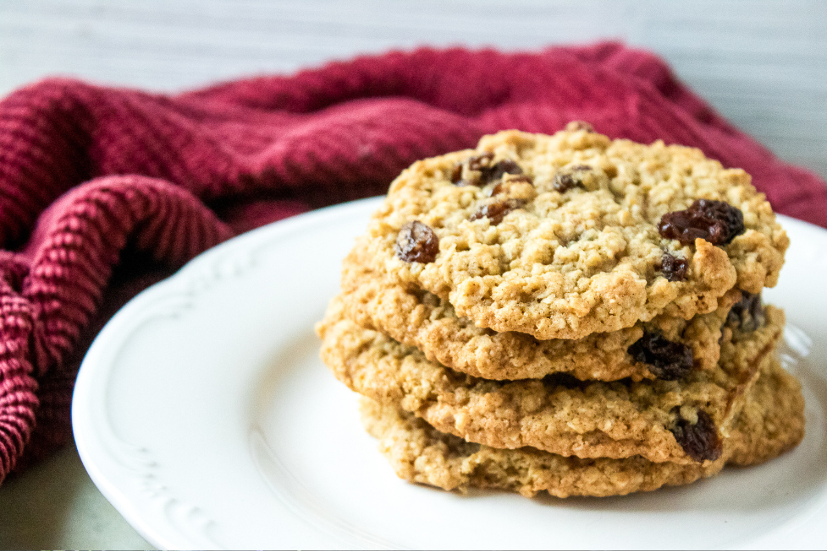 Hand holding a chewy oatmeal raisin cookie showing soft center and raisins