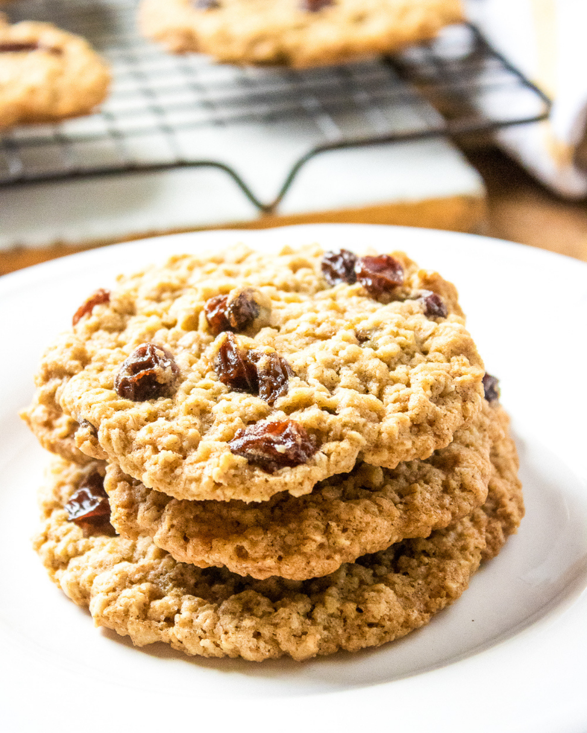 Fresh baked oatmeal cookies with raisins stacked on plate in kitchen setting