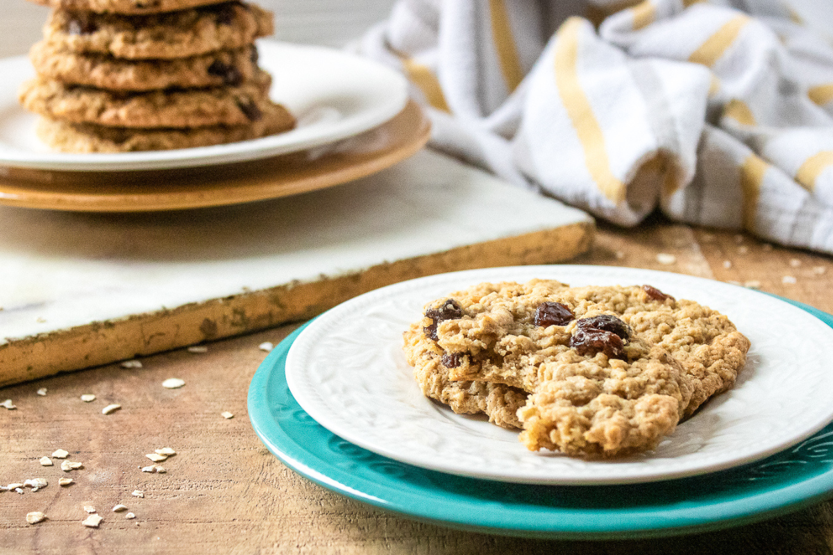 Homemade oatmeal raisin cookies stacked on plate with red kitchen towel