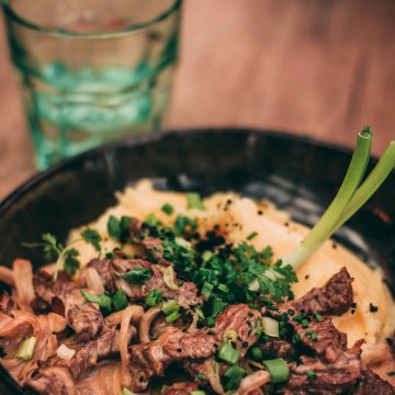 Delicious beef stroganoff served with creamy mashed potatoes, garnished with herbs.