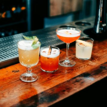 A vibrant selection of cocktails on a wooden bar, perfect for nightlife and parties.