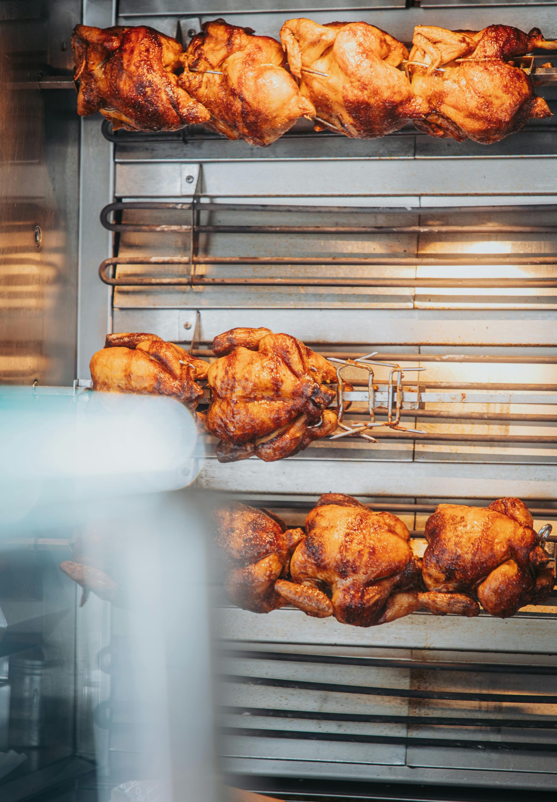 Mouthwatering rotisserie chicken cooked to perfection on a grill spit in a cozy indoor setting.
