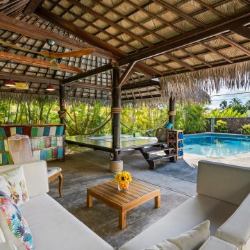 Tropical outdoor patio featuring a cabana, seating area, and swimming pool, perfect for luxury relaxation.