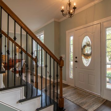 Inviting modern hallway with staircase, chandelier, and natural daylight.
