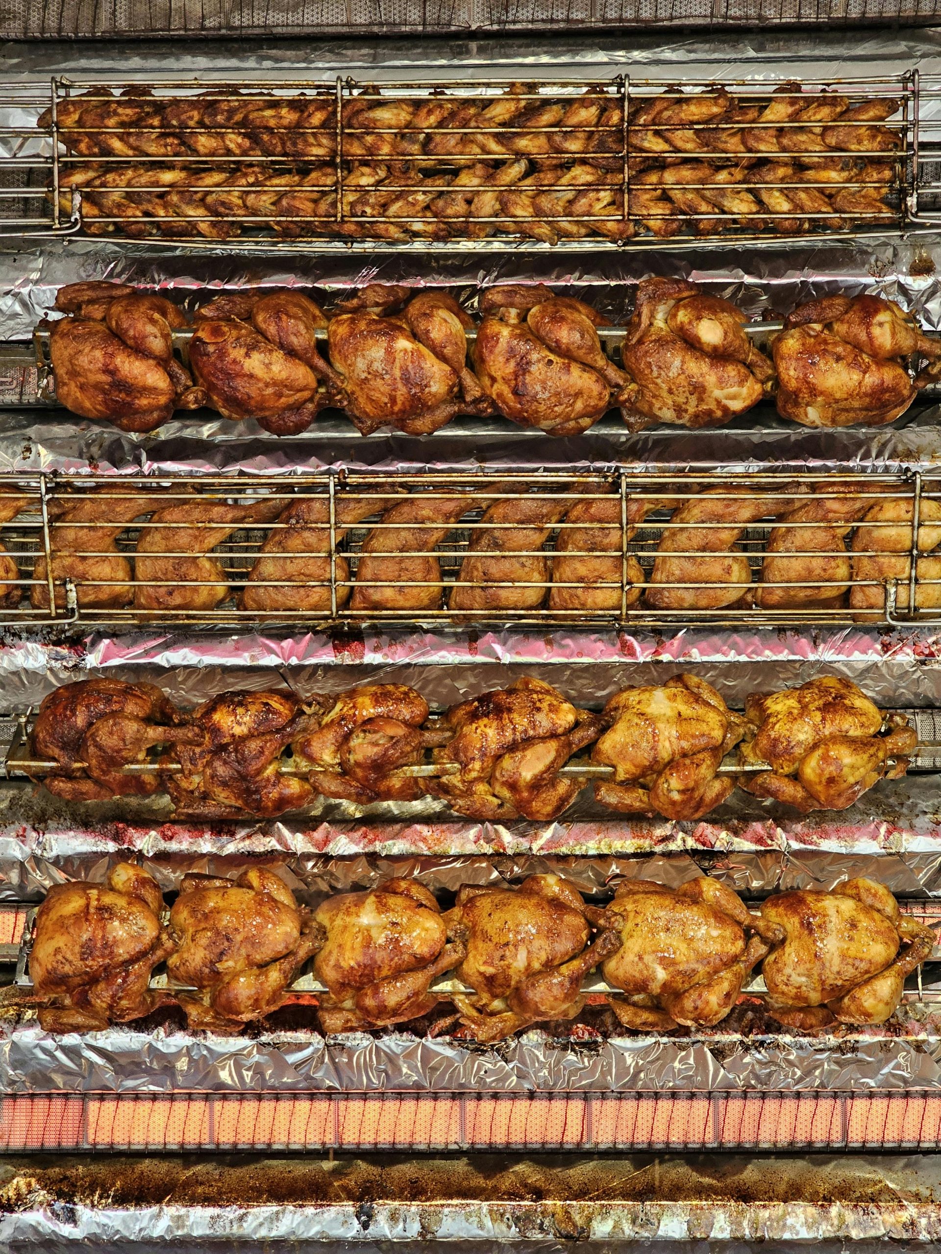 Rows of perfectly cooked rotisserie chickens and grilled meats.