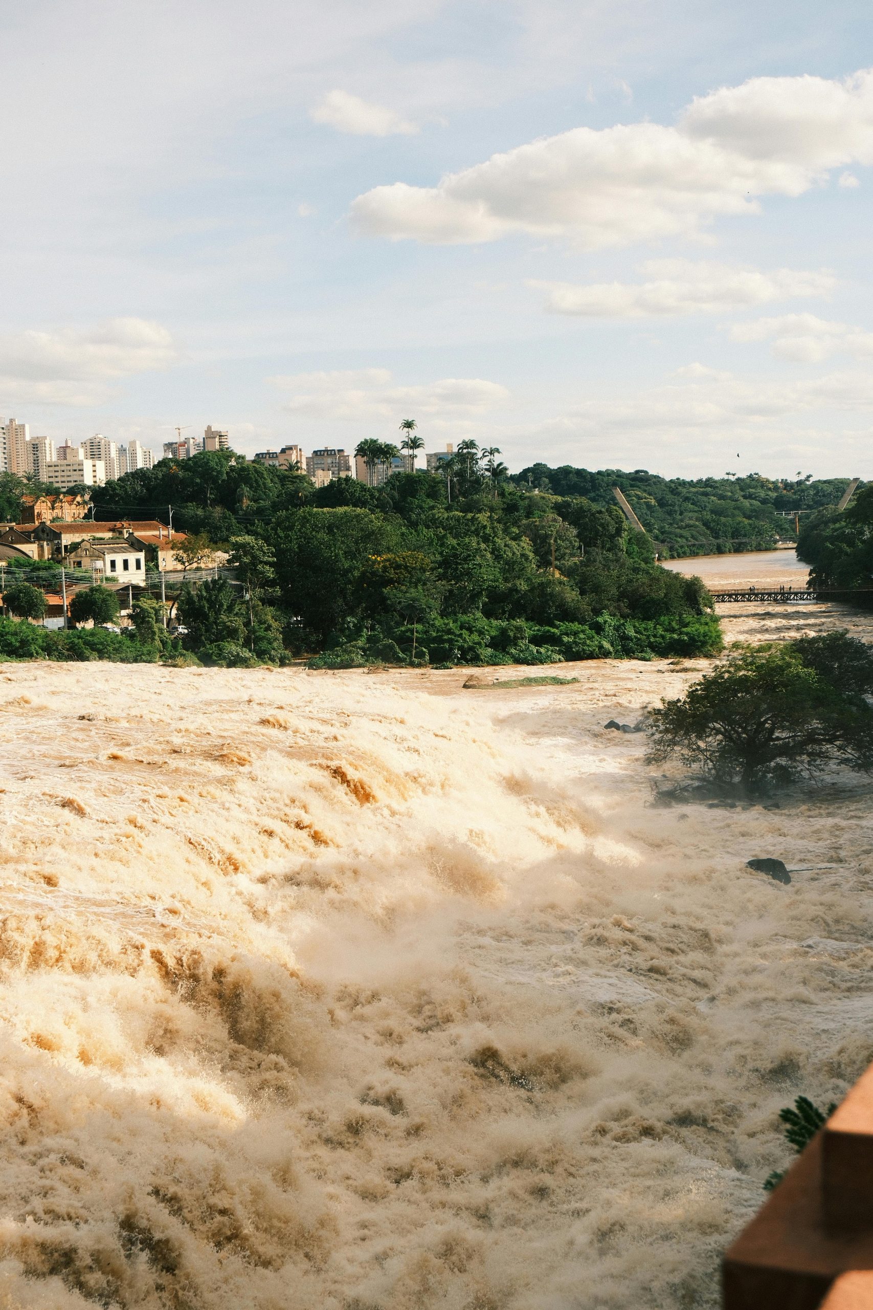Raging waterfall amidst lush greenery and cityscape in Piracicaba, State of São Paulo, Brazil.