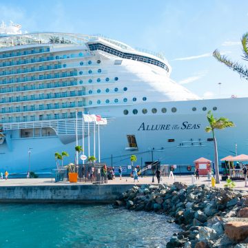 Discover the majestic Allure of the Seas docked in a vibrant tropical port.