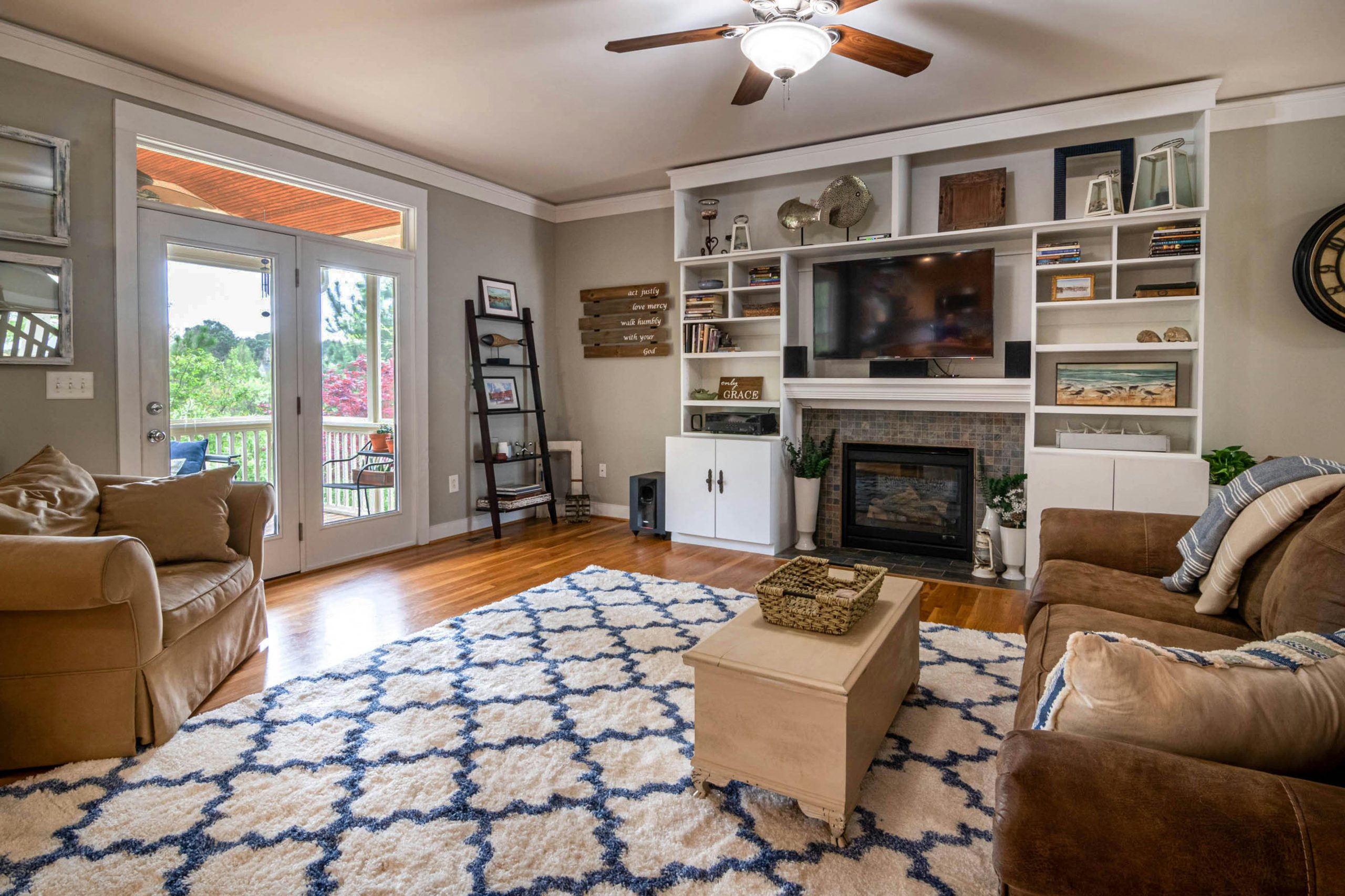 A stylish living room featuring a ceiling fan, fireplace, and elegant decor for a cozy atmosphere.
