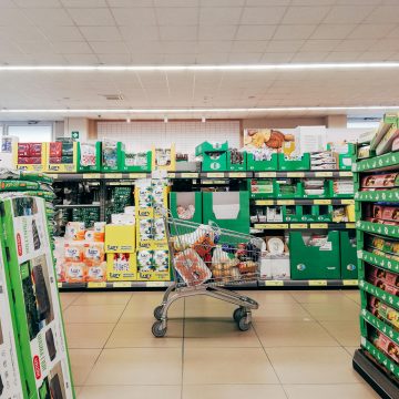 Shopping cart in a vibrant supermarket aisle in Padova, Italy.