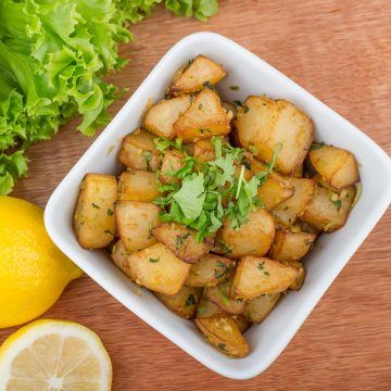 Spicy Lebanese batata harra served with lemon and lettuce.