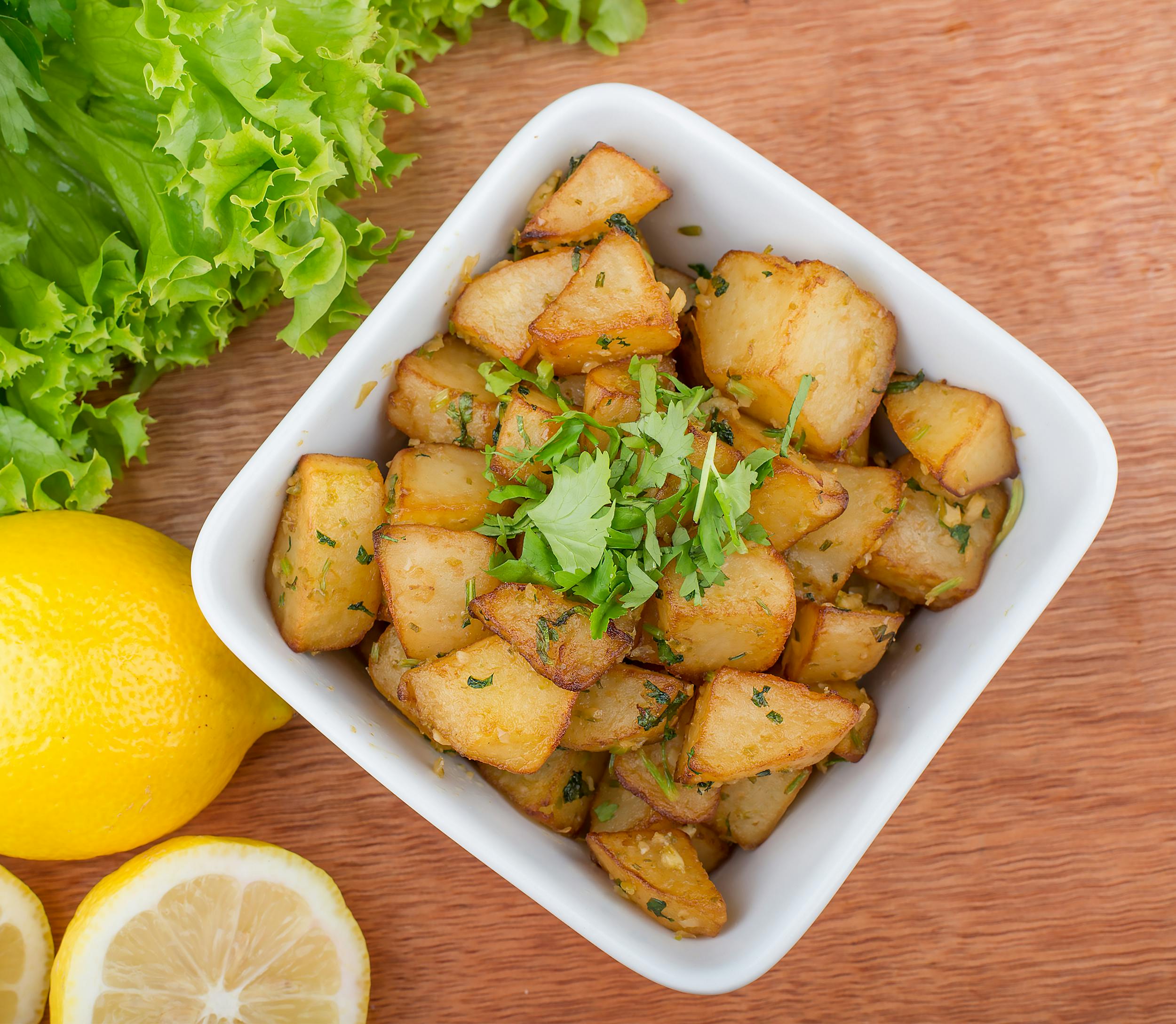 Spicy Lebanese batata harra served with lemon and lettuce.