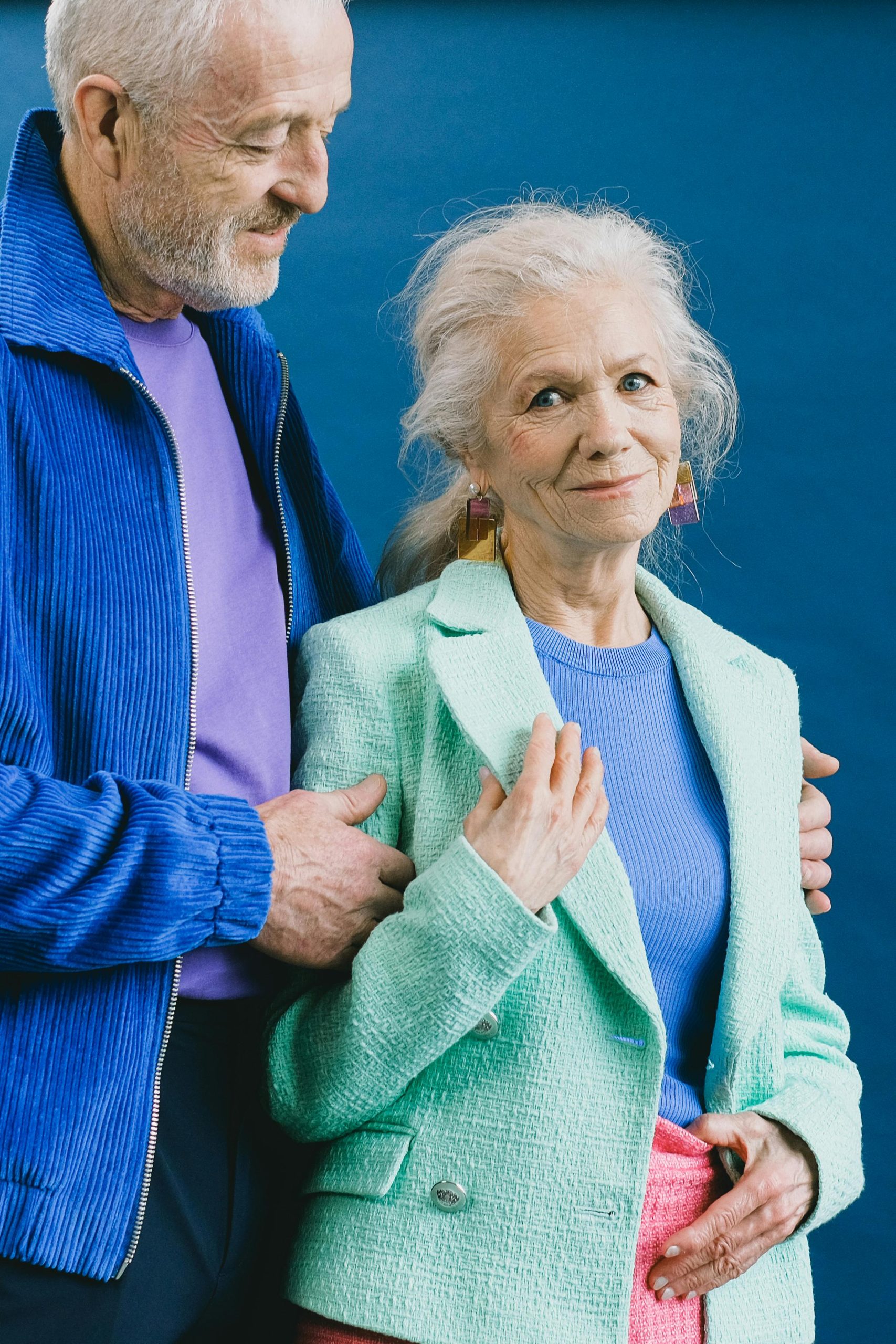 A senior couple in colorful outfits sharing a sweet and affectionate moment.