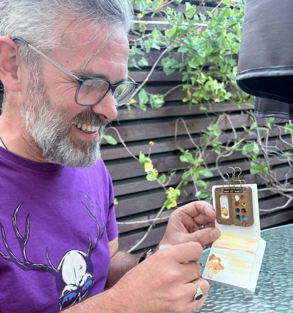 man looking at mini water color art