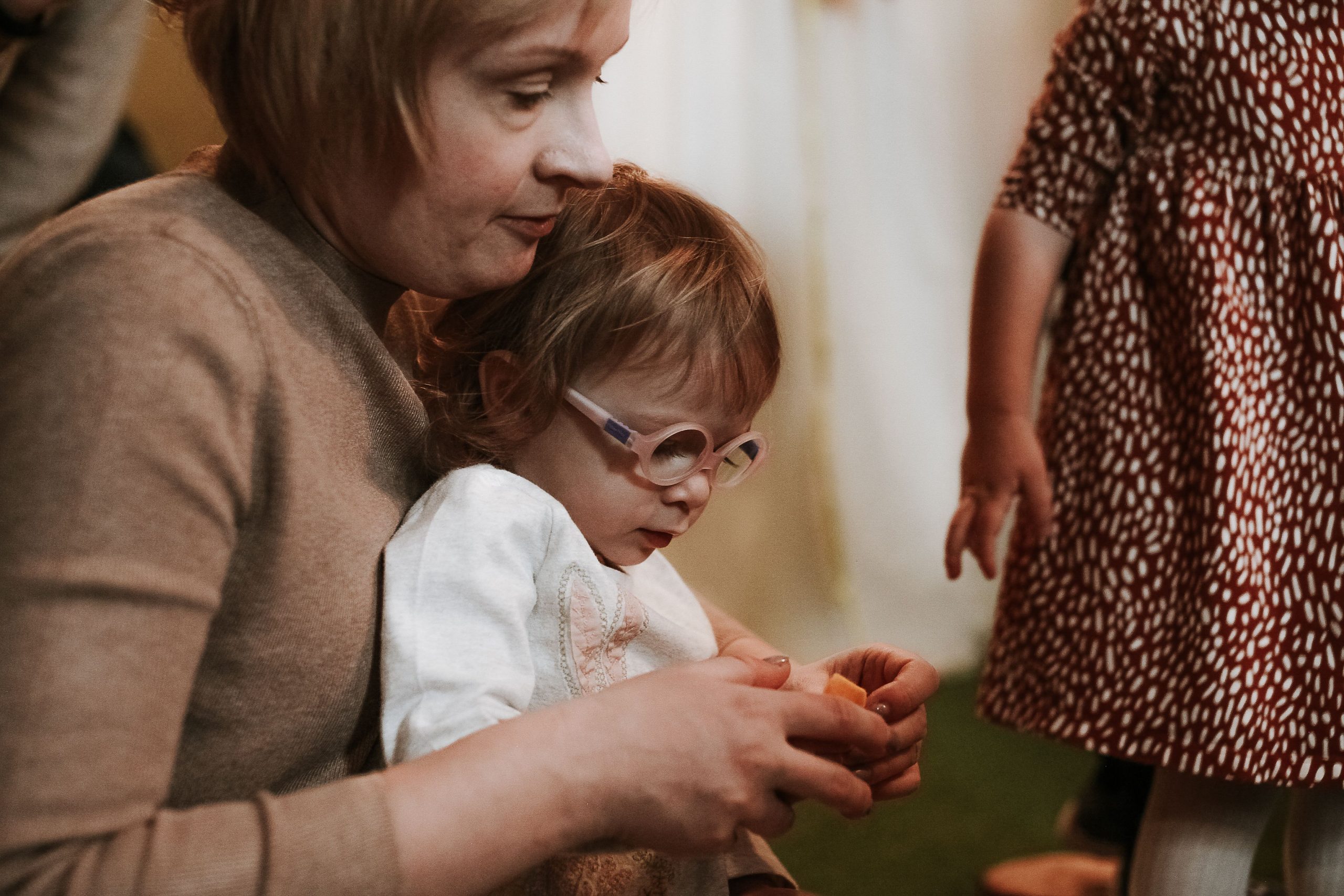 A touching portrait of a mother embracing her daughter wearing glasses, capturing love and tenderness.
