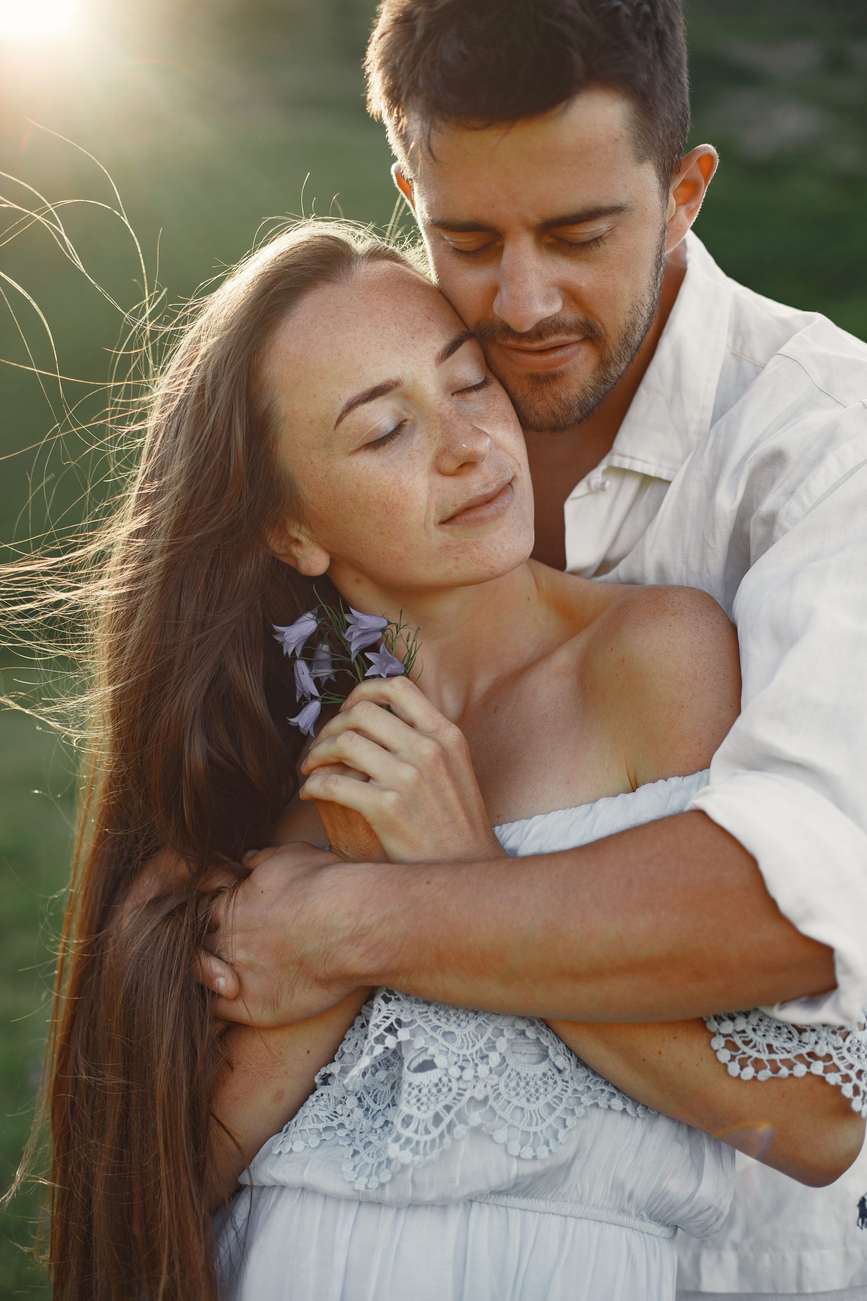 A loving couple embraces in a sunlit outdoor setting, enjoying a serene connection.