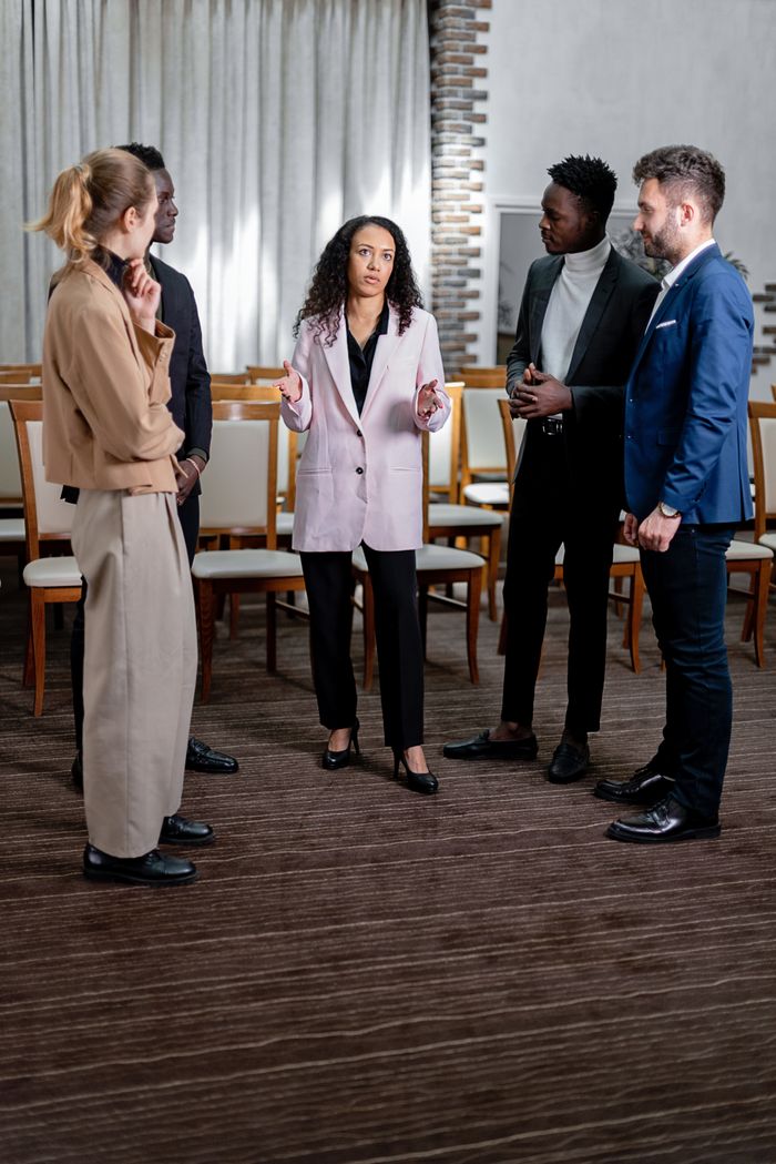 A diverse group of business professionals engaged in a serious discussion in an office setting.