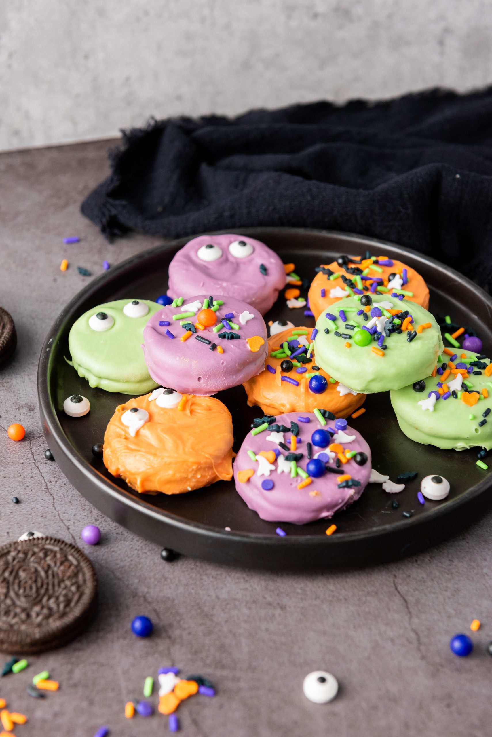 Halloween Oreos decorated with colorful candy melts, spooky candy eyes, and festive sprinkles for an easy Halloween treat.