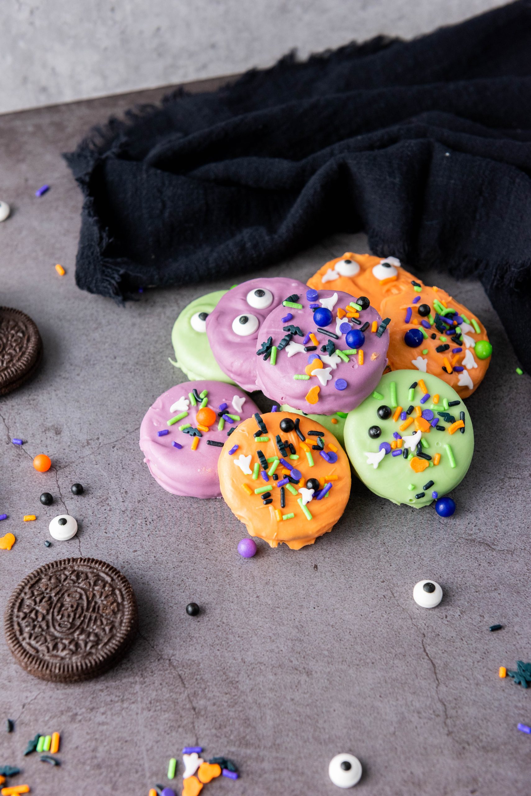 Halloween Oreos dipped in colorful candy coating and decorated with spooky candy eyes and festive Halloween sprinkles for a fun party treat.