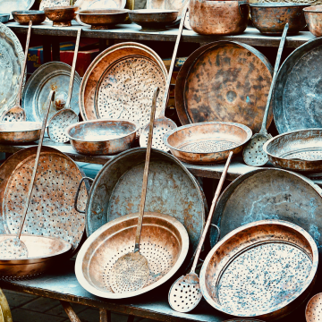 An assortment of vintage copper kitchenware displayed outdoors, showcasing rustic charm.