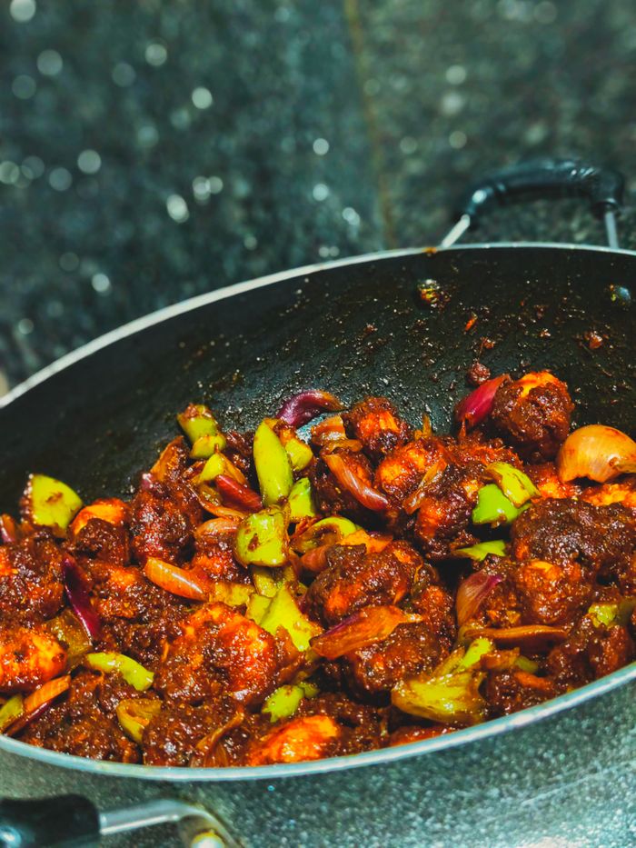 Spicy chilli prawns cooked with vegetables in a traditional Indian wok, showcasing vibrant flavors and colors.